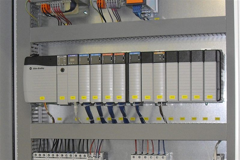 Industrial PLC control panel with modular I/O modules on DIN rail, similar to the compact modular architecture of the Omron NX1 Series
